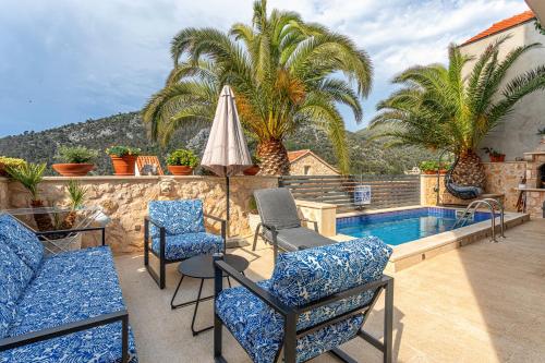 a patio with chairs and an umbrella and a swimming pool at Villa Capitis in the center - Apartment with private pool in Hvar