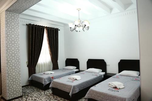 Habitación con 2 camas y lámpara de araña. en Demir Hotel Bukhara, en Bukhara