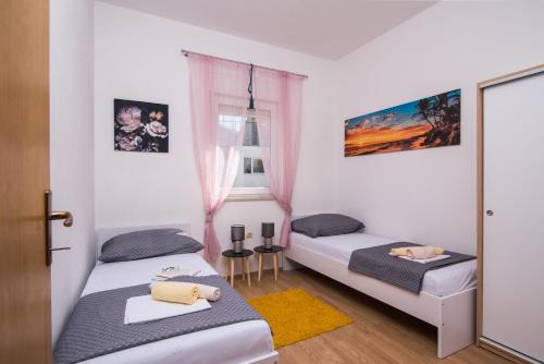a bedroom with two beds and a window at Apartments Marinera in Trogir