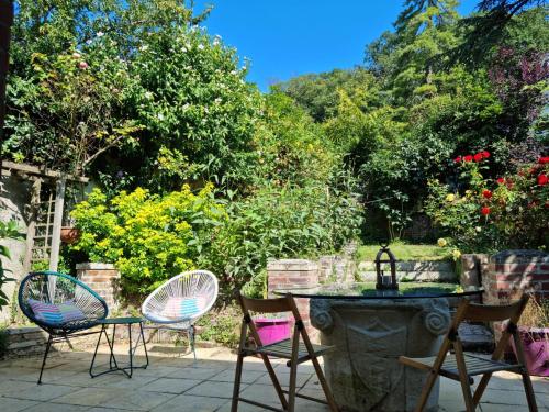a patio with chairs and a table with a fountain at Suite de charme avec JACUZZI illimité et jardin privatif in Saint-Prix