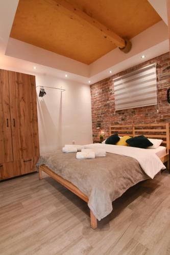 a bedroom with a large bed and a brick wall at GardenLux Vrdnik in Vrdnik