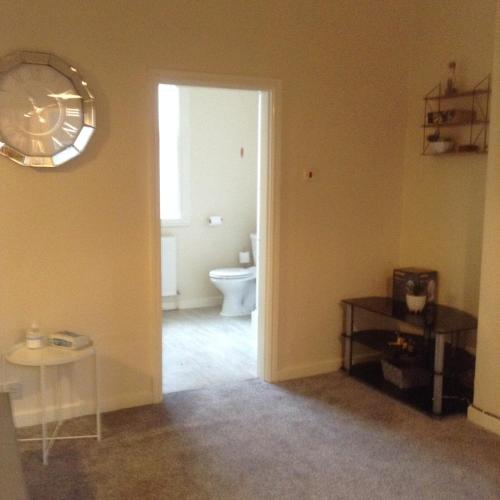a bathroom with a toilet and a clock on the wall at Marshfield Apartment in Goole