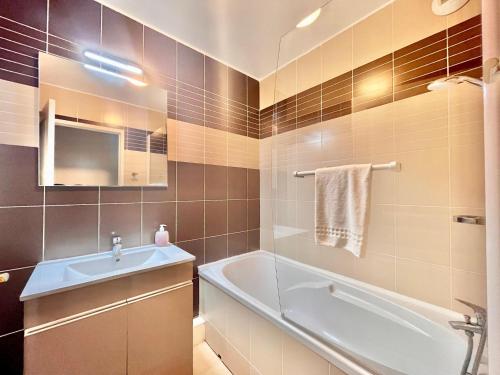 une salle de bain avec une baignoire et un lavabo et une baignoire dans l'établissement Résidence La Ferme de Deauville - Saint Arnoult, à Saint-Arnoult