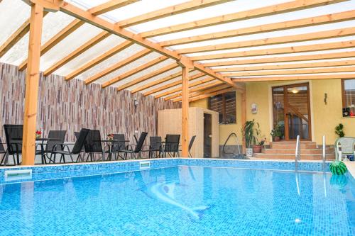 a swimming pool with a wooden pergola and tables and chairs at Hotel Saint Nicola in Banya