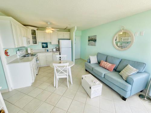 a living room with a blue couch and a kitchen at #908 Lovers Key Beach Club Gulf View in Fort Myers Beach