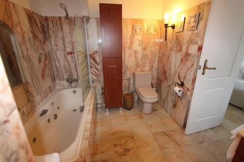 e bagno con vasca, servizi igienici e lavandino. di Espectacular casa en la playa a Fuengirola