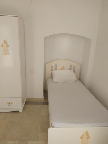 a small white bedroom with a white bed in it at Maison Bleu in Hammamet
