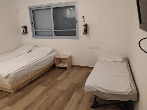 1 dormitorio con cama, ventana y silla en מדבריות השחר, en Dimona