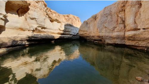 un cuerpo de agua en un cañón con rocas en מדבריות השחר, en Dimona