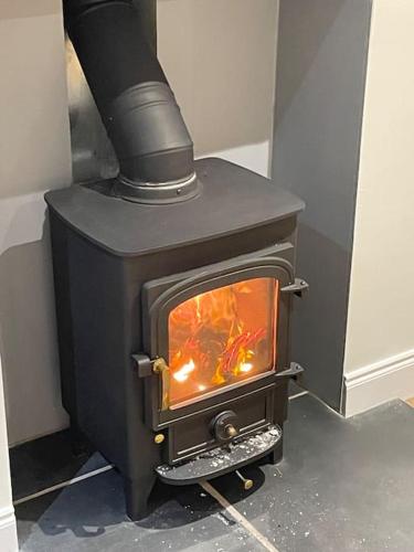 a black stove with a fire inside of it at Holiday House at 22, Contemporary 3 bedroom cottage in historic Wigtown in Wigtown