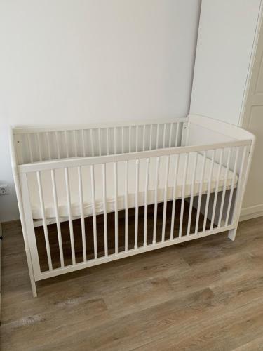 a white crib in a room with a wooden floor at Noorhus - Kurzurlaub an der Ostsee in Maasholm