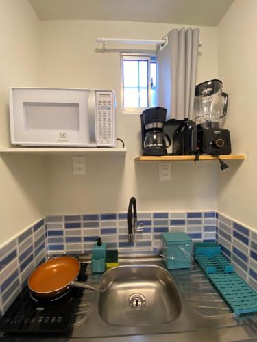 um balcão de cozinha com um lavatório e um micro-ondas em CASA PITANGA em Fernando de Noronha