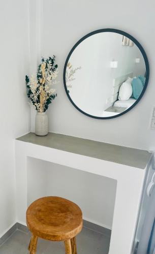 a round mirror on a shelf with a wooden stool at Kirki Rooms by the sea in Parikia