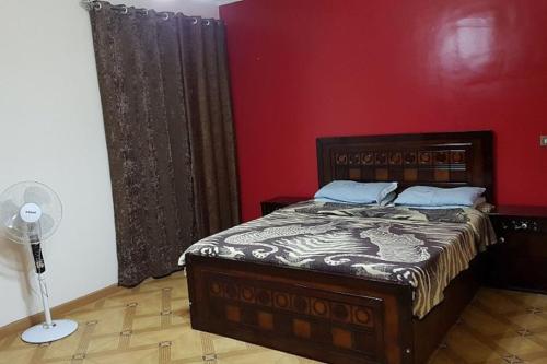 1 dormitorio con cama y pared roja en Fantastic Apartment Near Cairo Airport en El Cairo