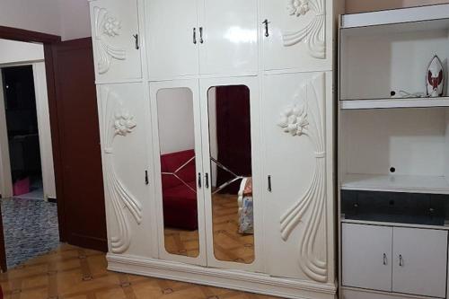 a white cabinet with mirrors in a room at Fantastic Apartment Near Cairo Airport in Cairo