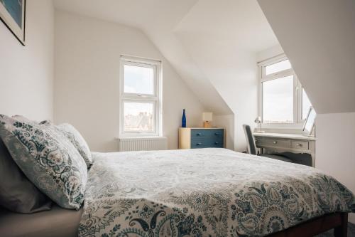 a bedroom with a bed and a desk and windows at Private Two Bedroom Residence in Southbourne - Private Parking - Off the High Street - Minutes Away from the Beach in Bournemouth