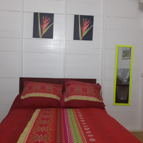 a bedroom with a red bed with pictures on the wall at Bungalow Vernou Petit-Bourg in Petit-Bourg