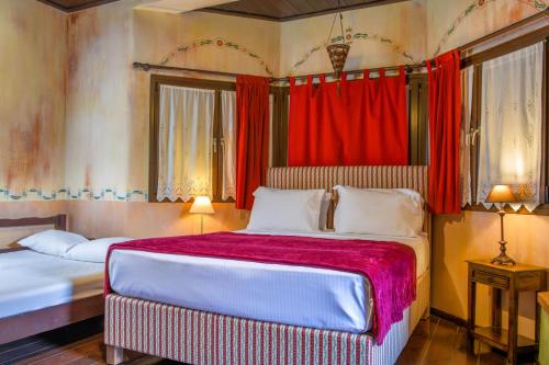 a bedroom with two beds and red curtains at Monastiri Guesthouse in Kalabaka