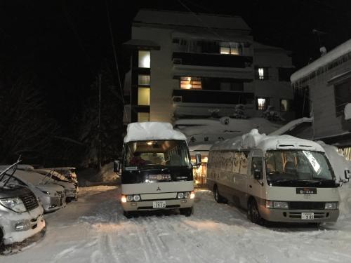 a truck and a van in the snow at night at Kofukan in Myoko