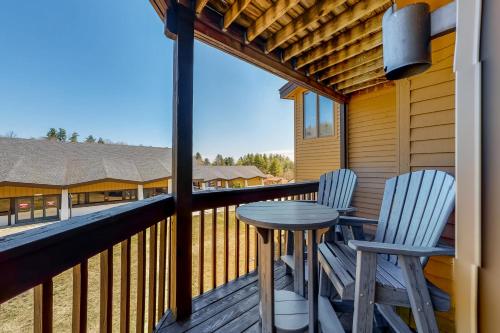 a porch with two chairs and a table on a deck at Okemo Mountain Lodge B203 in Ludlow
