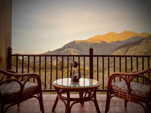a table and two chairs on a balcony with mountains at The Capoe House in Haputale