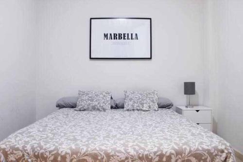 un letto in una camera bianca con una foto sul muro di BEST LOCATION apartment in MARBELLA. BEACHFRONT!! a Marbella