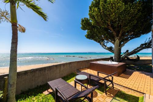a patio with two chairs and a table next to the beach at Pine House in Ginoza in Ginoza