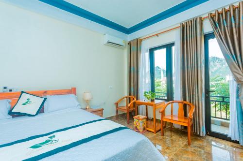 a bedroom with a bed and a desk and windows at Phong Nha Green Homestay in Phong Nha