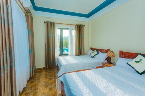 a bedroom with two beds and a window at Phong Nha Green Homestay in Phong Nha