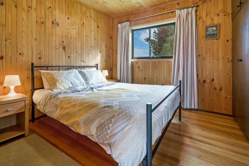 ein Schlafzimmer mit einem Bett in einem Zimmer mit einem Fenster in der Unterkunft Blackwood Park Cottages Mole Creek in Mole Creek