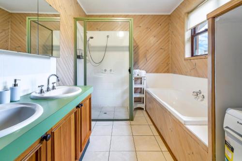 y baño con 2 lavabos, bañera y ducha. en Blackwood Park Cottages Mole Creek, en Mole Creek