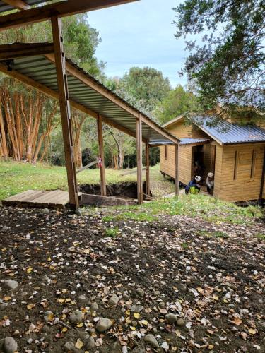 a house with a porch and a person sitting in a yard at El refugio del Volcan Osorno in Puerto Clocker