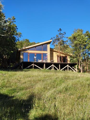 a house on top of a grassy hill at El refugio del Volcan Osorno in Puerto Clocker