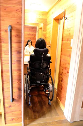 a woman sitting in a wheelchair in a room at Nabekura Kougen Mori-No-Ie in Iiyama