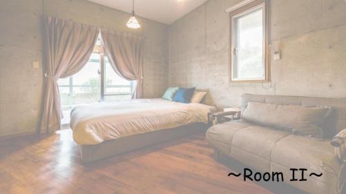 a bedroom with a bed and a couch and a window at Pine House in Ginoza in Ginoza