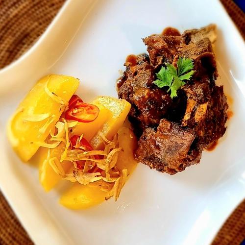a plate of food with meat and vegetables on it at Cersen Resort Lombok in Kuta Lombok
