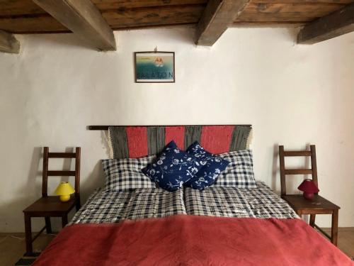 ein Schlafzimmer mit einem Bett mit blauen Kissen darauf in der Unterkunft Káli Kerted Vendégházak Karolin néni háza in Monoszló