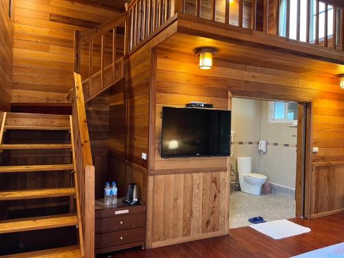 a bedroom with a staircase and a television in a cabin at Ye Jiang Hua Homestay in Meishan