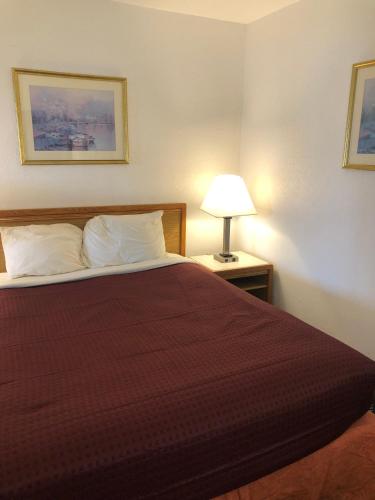 um quarto de hotel com uma cama com uma colcha vermelha em Four Winds Motel em Depoe Bay