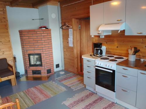 a kitchen with a stove and a brick fireplace at Kuvalusdream Chalet in Lintusalo