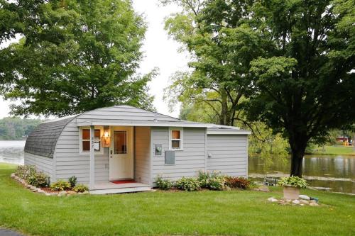 a small shed in the grass near a body of water at Cozy Quonset Hut On Maple Lake in Paw Paw