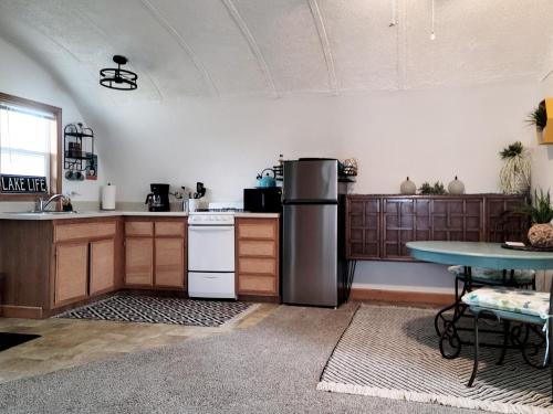 a kitchen with a refrigerator and a table at Cozy Quonset Hut On Maple Lake in Paw Paw