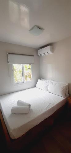 Cama blanca en habitación con ventana en AM Residences, en Panglao