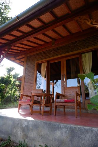 a porch of a house with chairs and windows at Saridevi Ecolodge in Jatiluwih