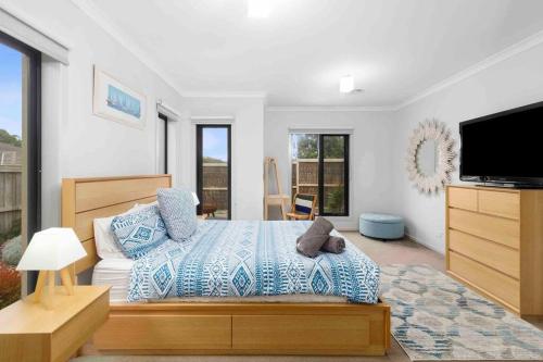1 dormitorio con 1 cama y TV de pantalla plana en Corymbia Barwon Heads Modern Family Getaway!, en Barwon Heads