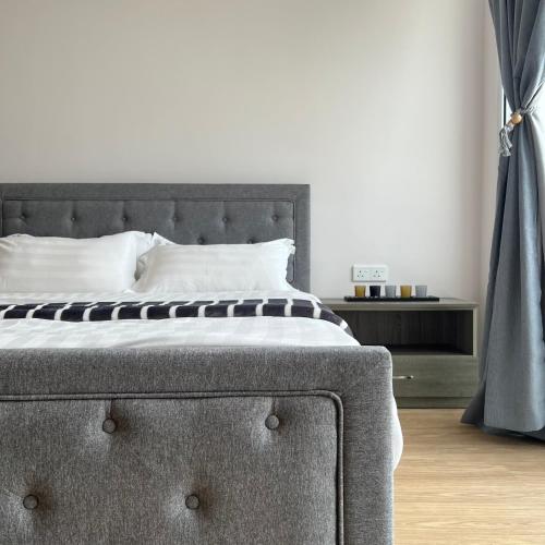 a bedroom with a bed with a gray headboard at AruSuites Tanjung Aru Kota Kinabalu By LAXZONE in Kota Kinabalu