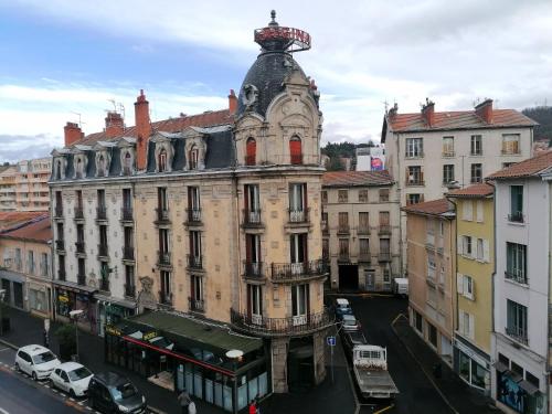an old building with a clock tower in a city at Hôtel et Restaurant Le Regina in Le Puy-en-Velay