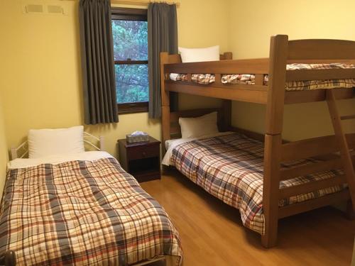 a bedroom with two bunk beds and a window at Julian's English Homestay and Pension in Fujimi