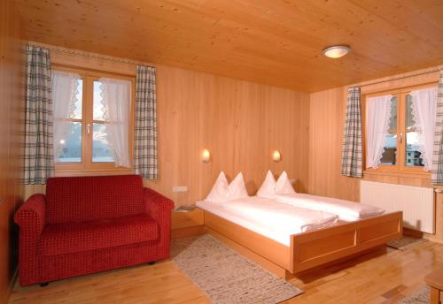 a bedroom with a bed and a red chair at Haus Schatz in Schoppernau