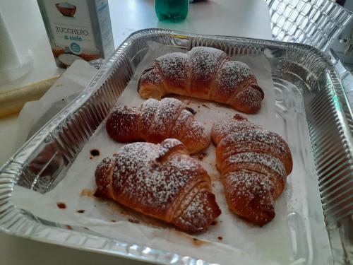 three croissants in a baking pan with powdered sugar at Blu oceano B&B, Italian restaurant in Nembrala
